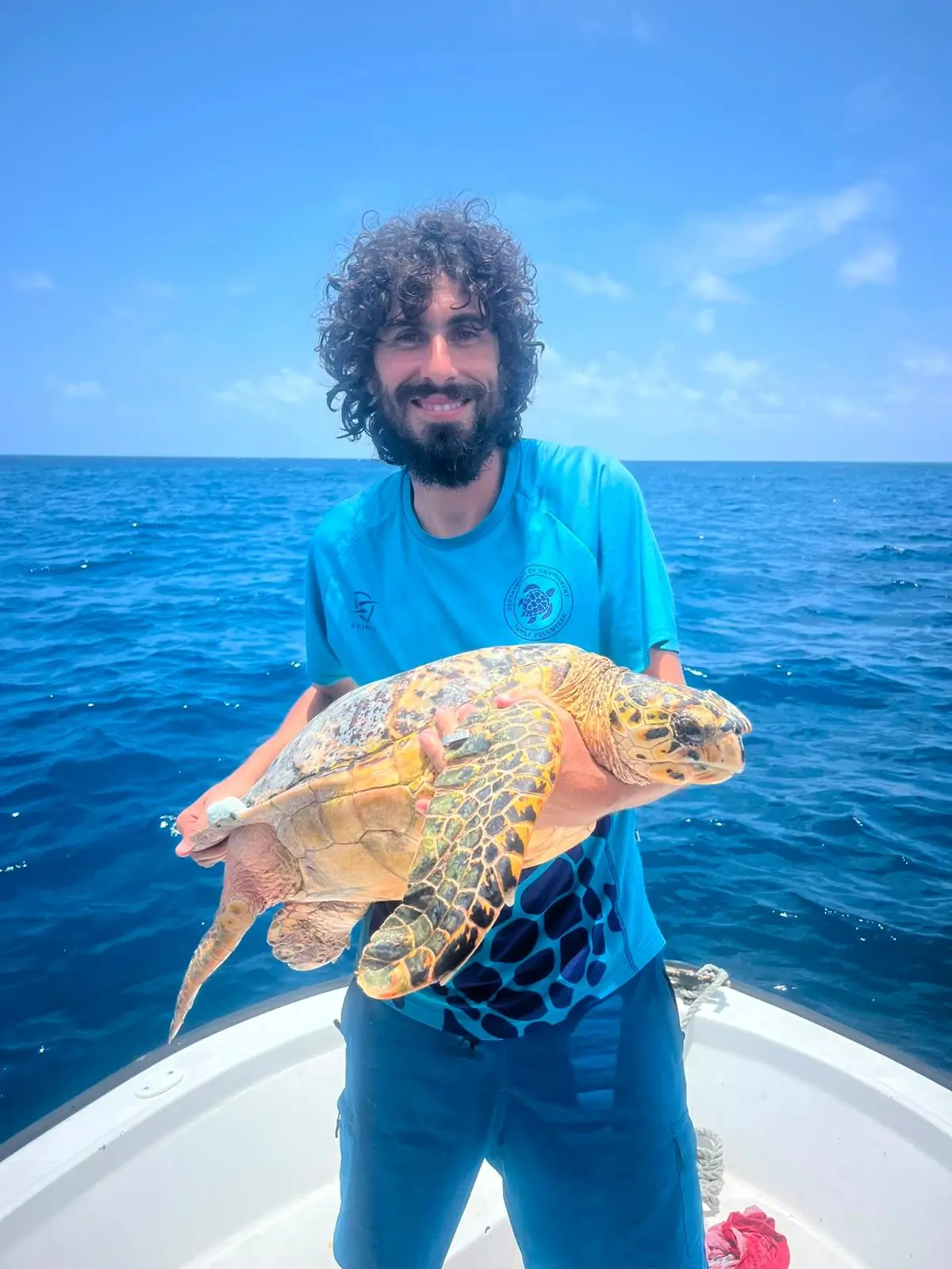 Alejandro Prat Varela, Project Lead, holding a hawksbill turtle aboard a Cayman Islands Department of Environment research boat