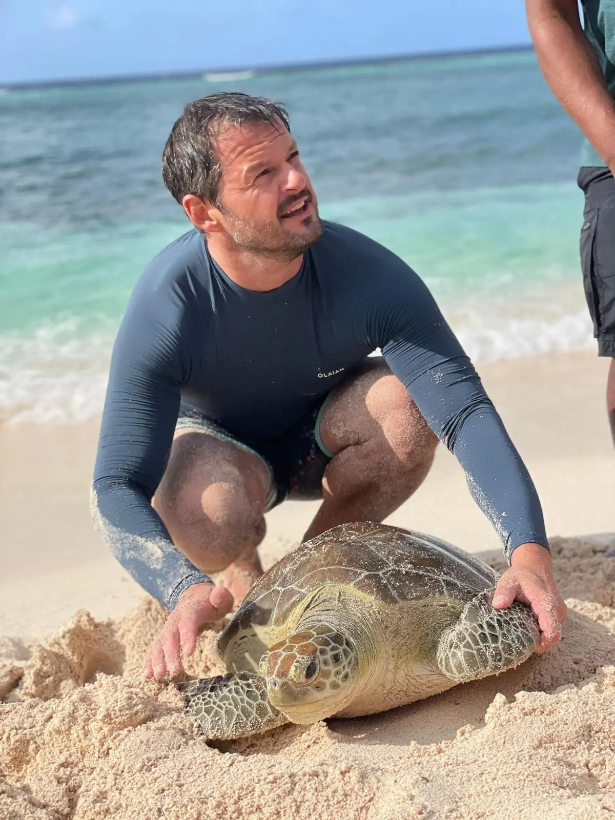 Joseph Roche Chaloner, Field Lead, releasing a green turtle on a Cayman beach
